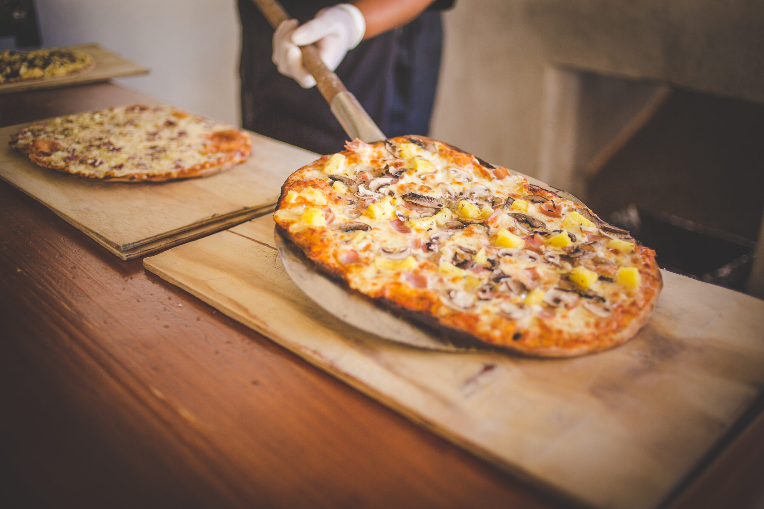 Close up image of a freshly baked gourmet wood fired pizza as it gets taken out of the pizza oven Pizza